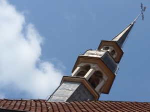 Small church tower in front of a blue sky
