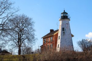 White-washed lighthouse and a red brick house.