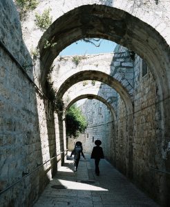 Two kids on the arch-covered St. James Street in Jerusalem.
