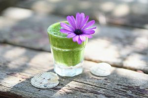 Green juice adorned with a violet flower.