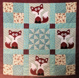 Handsewn quilt by Rebecca Holmlund.  Panels have cartoon-like foxes on them.
