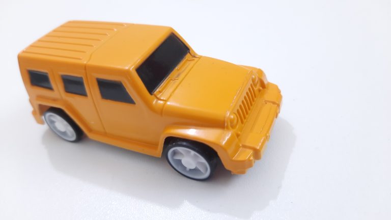 An orange toy SUV on a white surface