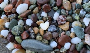 White heart-shaped rock on pile of colorful rocks