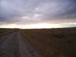 Dusty road across the desert under a cloudy sky