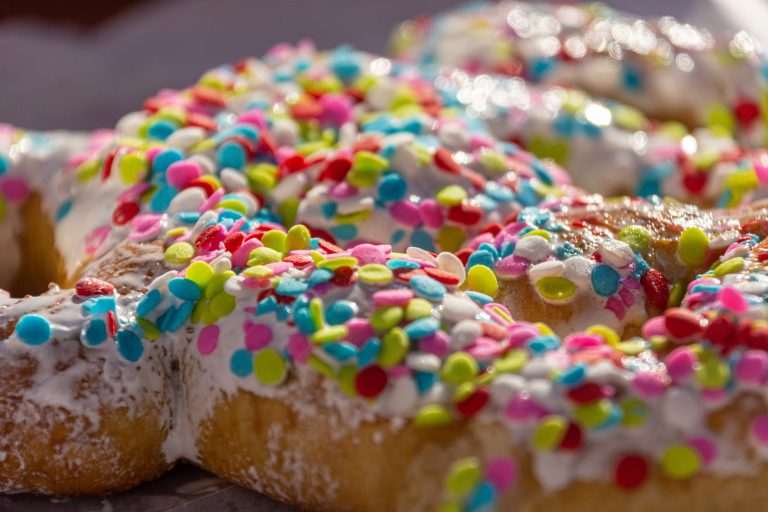 Neon sprinkles on top of a frosted pretzel