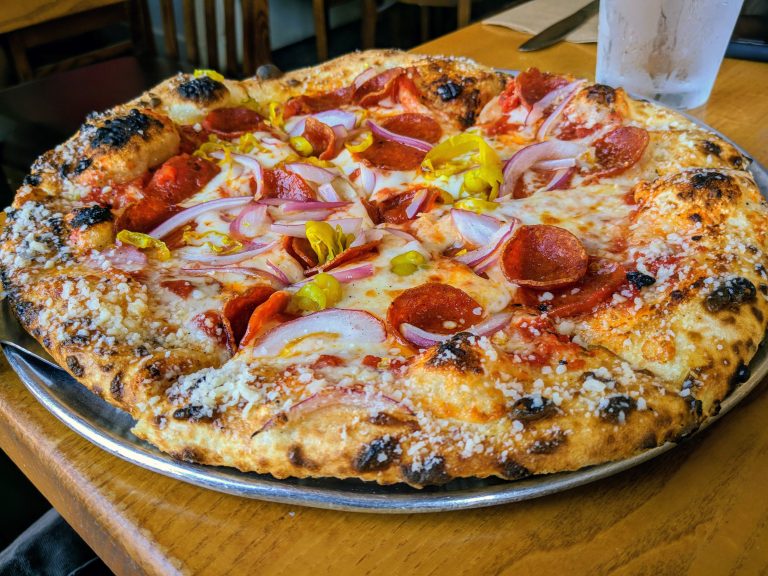 A fresh wood-fired pizza with pepperoni and banana peppers