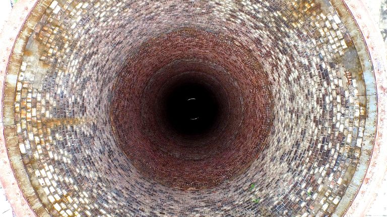 Looking down a disused power station chimney. Aerial drone footage.