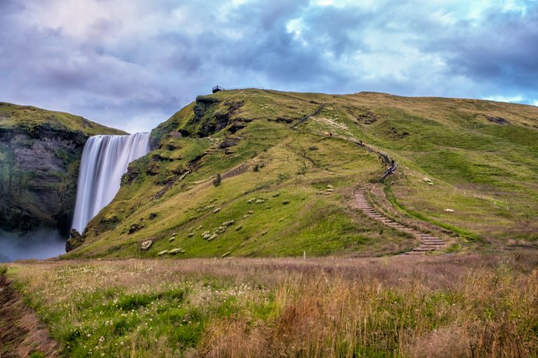 Admiring the winding staircase that leads to the top of Skógafoss in the South of Iceland. Skógafoss is one of the biggest waterfalls in the country with a width of 15 meters and a drop of 60 meters.