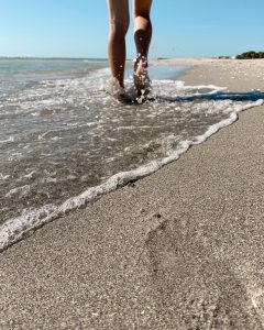 Legs walking in the shallow waves along the beach