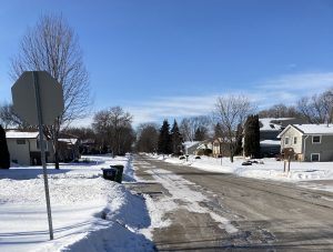 View larger photo: A street view of houses with snow covered roofs and backyards