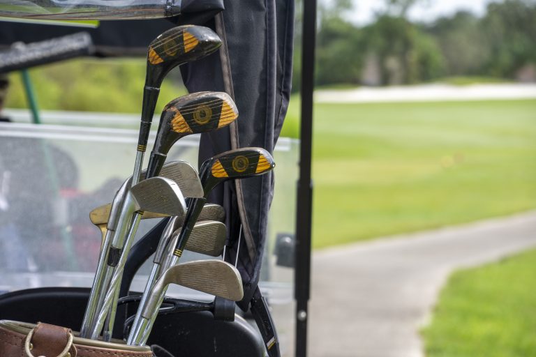 Golf clubs sticking out of a bag on the back of a golf cart