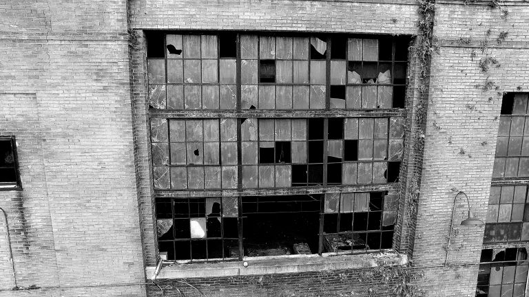 Broken windows in black & white of a disused power station.