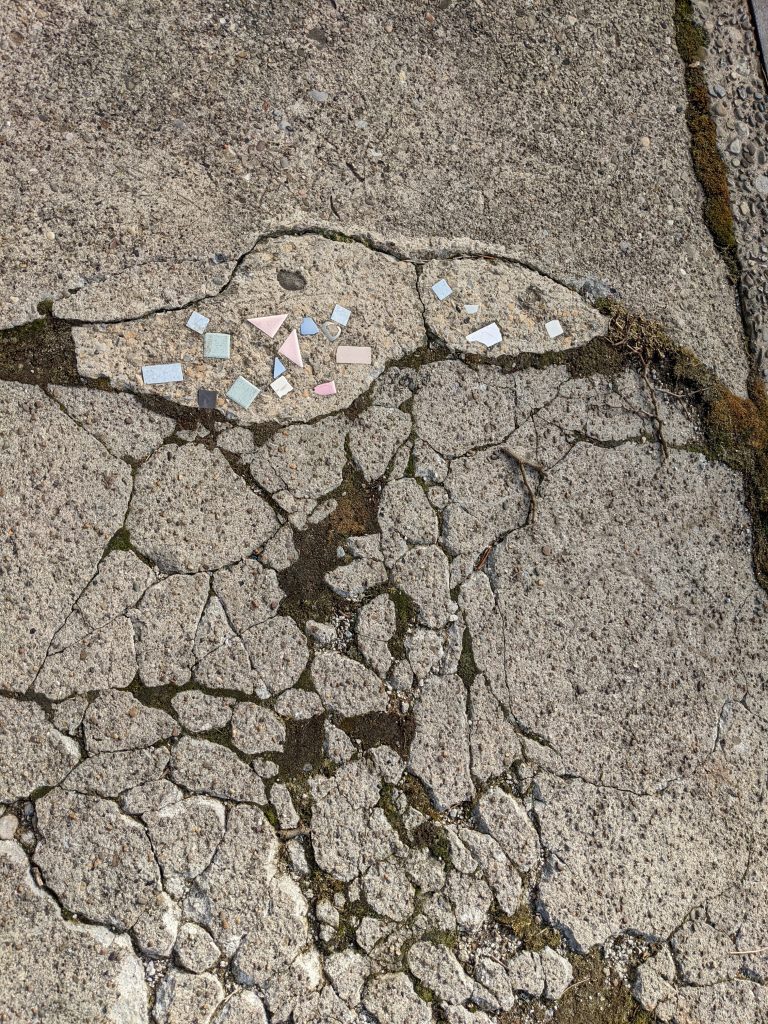 Broken sidewalk concrete with some tiles and such in it.