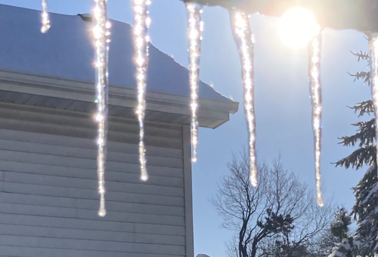 Roof gutter snow icicles against the sun