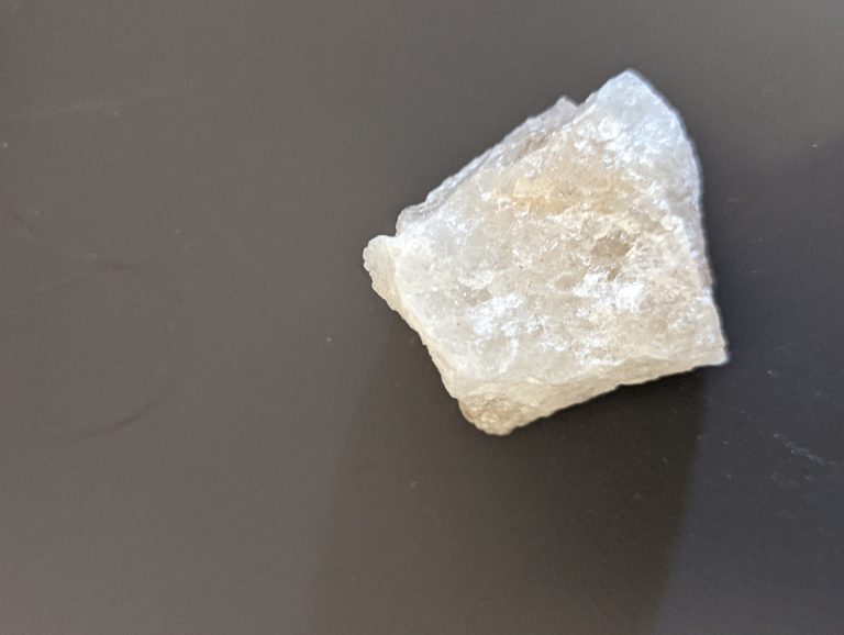 One white rock, slightly transparent, on a table.