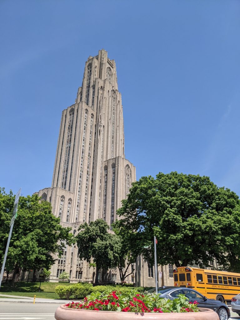 Pittsburgh’s Cathedral of Learning behind some trees and in front of a blue sky