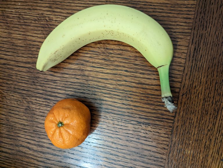 A small orange and a banana on a table