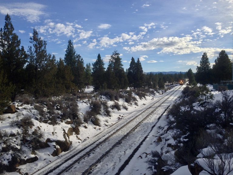 A train approaches in a snowy cut through the forest of central Oregon.