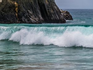 Waves crashing onto shore in California with cliffs in the background