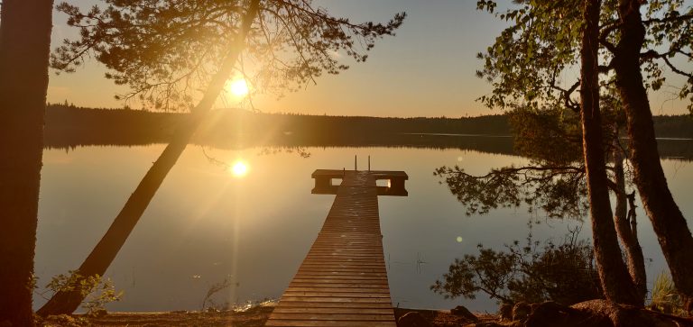 Sunset over lake with pier and forest in background