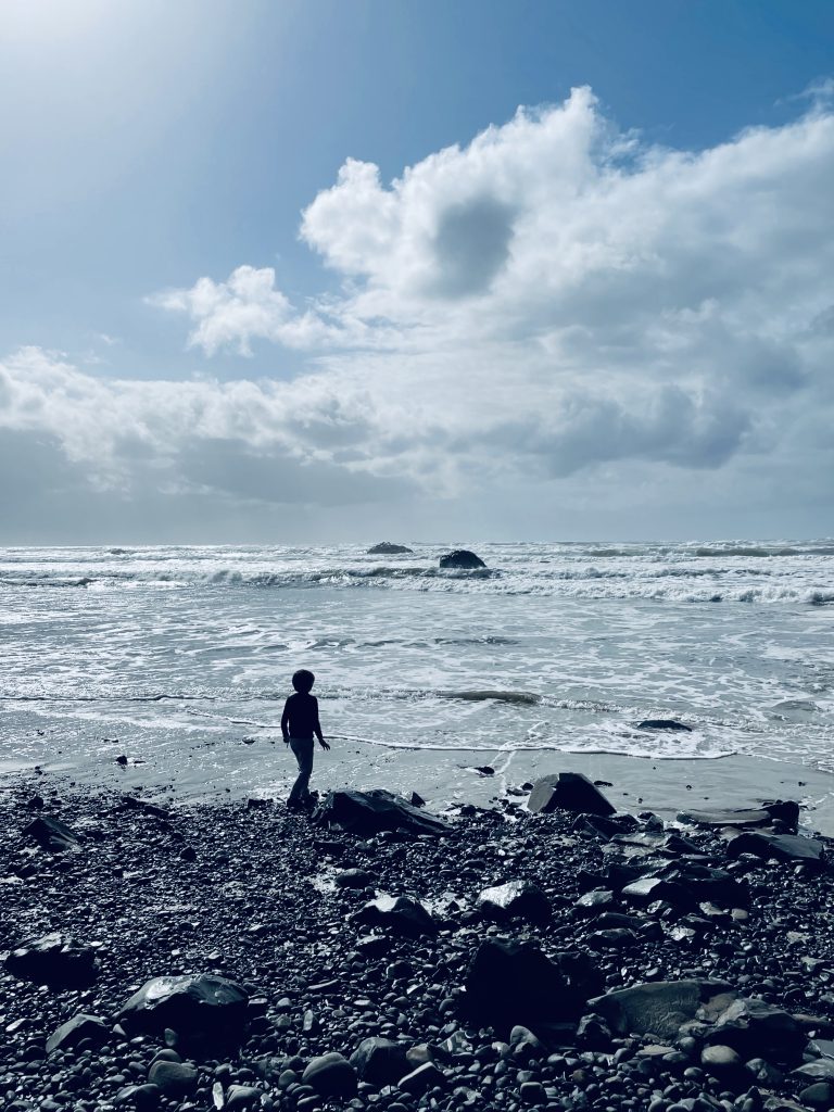 Rocky beach with a child looking out at the vast ocean