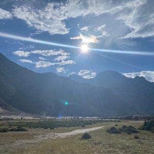 A scenic view of a mountainous landscape under a bright blue sky with scattered clouds.