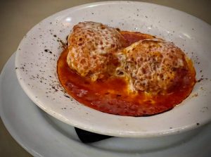 Two meatballs with cheese melted on top at an Italian restaurant
