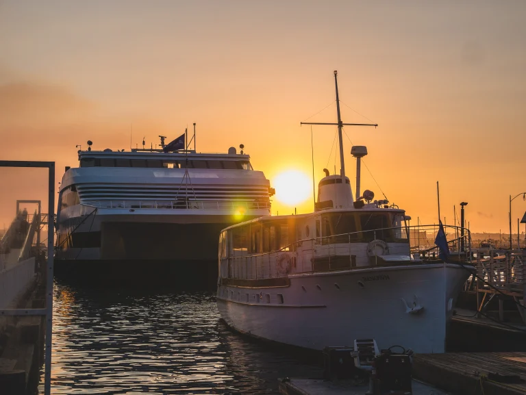 Large boats in the San Diego harbor with the sunset behind them