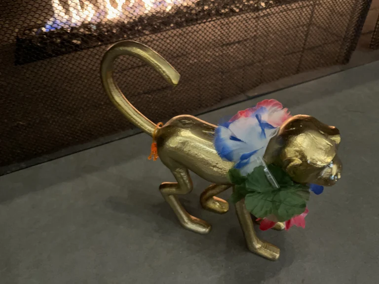 Decorated metalic monkey by the fire.