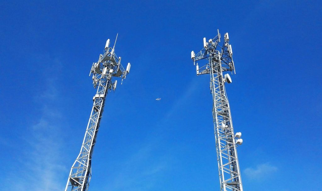 Airplane passing between two communication towers.