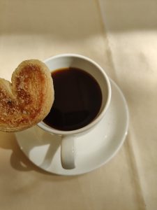 A cup of coffee with a cookie.
