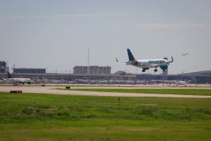 A Frontier Airlines plane lands while a Delta Airlines plane takes off
