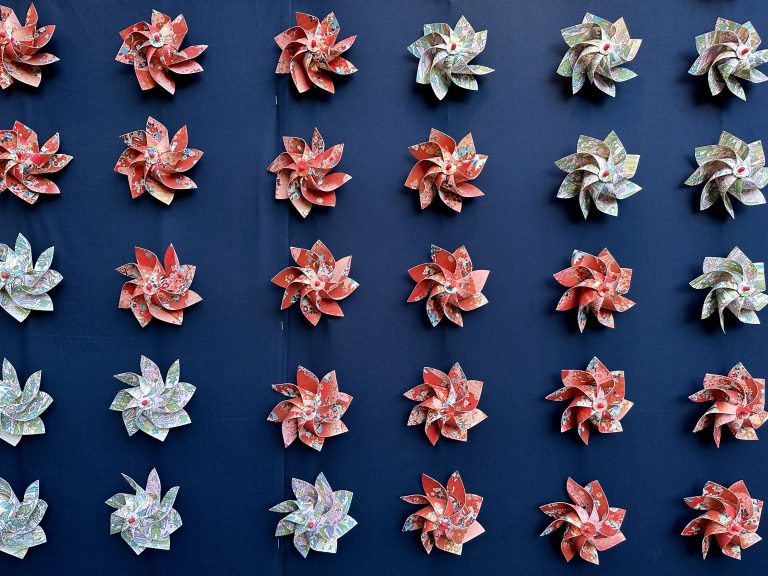 Five rows of Japanese paper pinwheels arranged regularly on a wall.