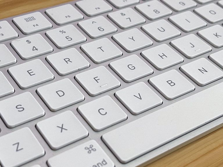 White Apple keyboard on a bamboo desktop.