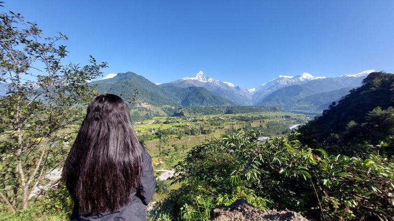 A girl enjoying the view of valley beneath the mount fishtail