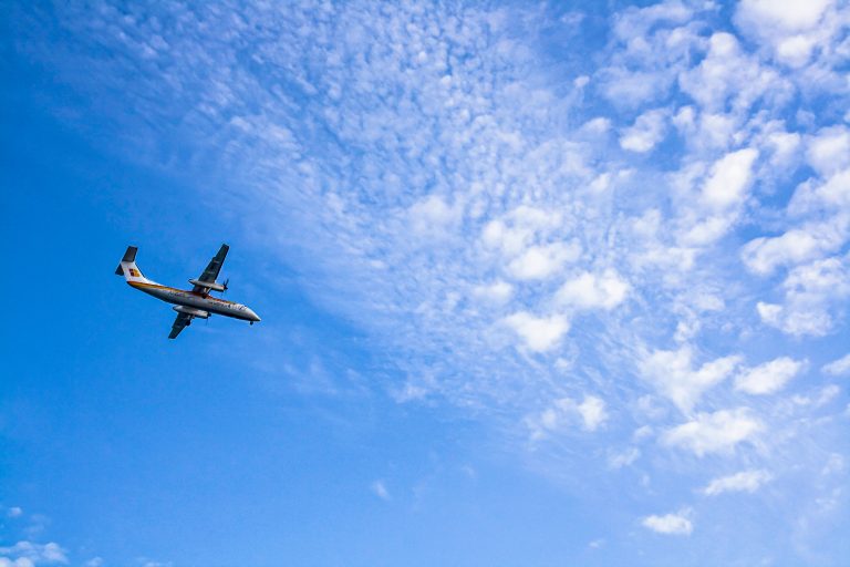 A plane flying on a blue cloudy sky.