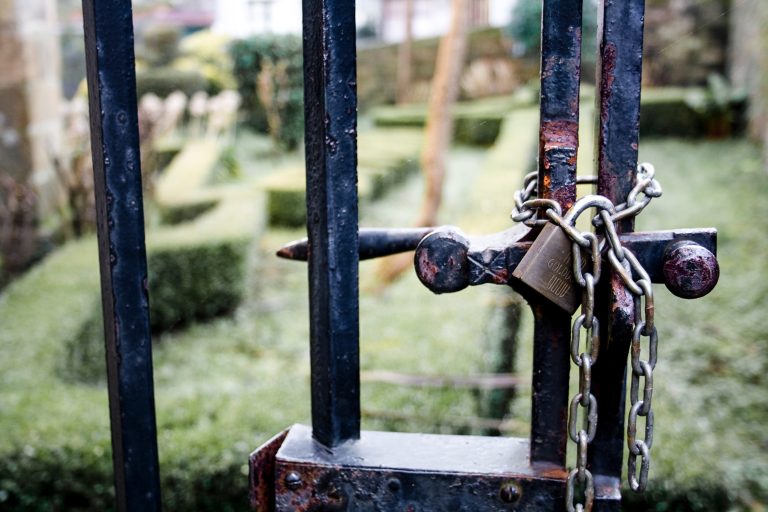 Rusty fence tied with chains and locked with a padlock.