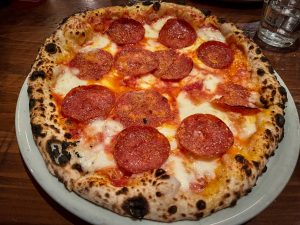 Pepperoni pizza cooked in a wood fire brick oven.