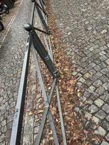 View larger photo: Autumn leaves around a fence in cobblestones. Milan, Italy