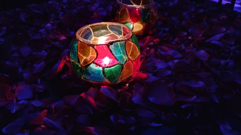 Candle light glass on table. With colourful decoration.