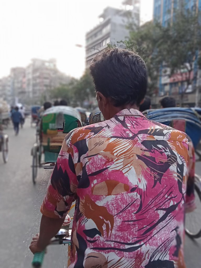 A rickshaw puller driving his rickshaw in the street of Dhaka, Bangladesh.