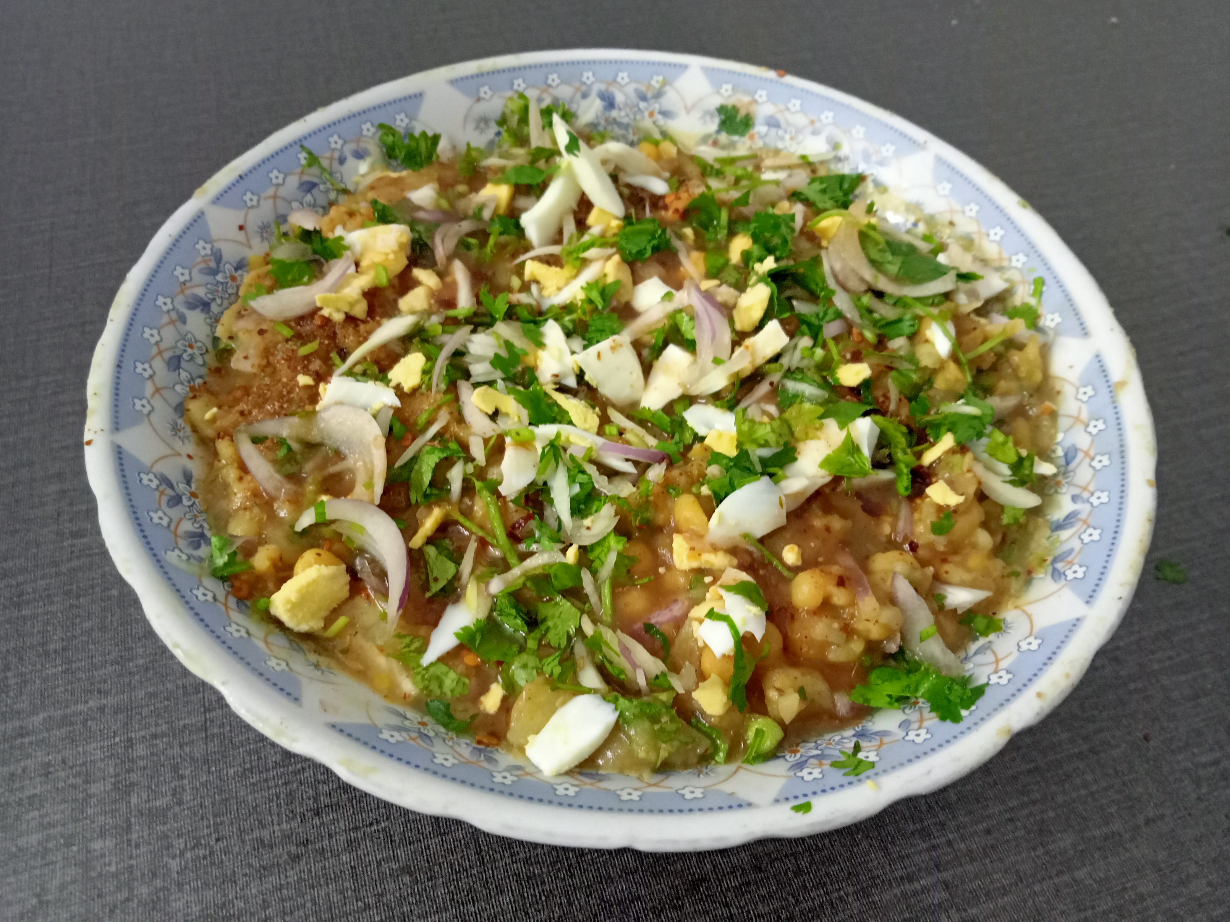 Chatpati / chotpoti, a Bengali street food mostly popular in Bangladesh, which consists mainly of potatoes, chickpeas, and onions and is usually topped with additional diced chillies or grated boiled eggs.