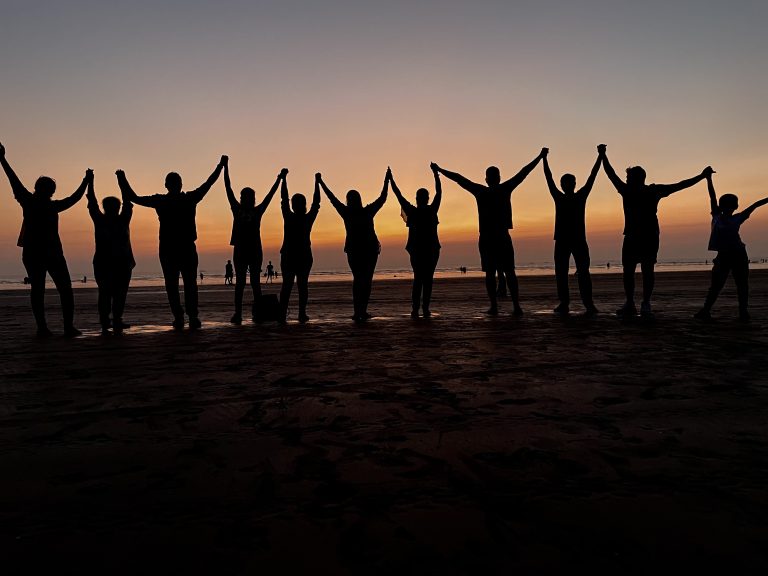 Photo which is about unity of friends, Sunset beach with friends, people in dark stand, people in sunset, people on beach, people hold hand