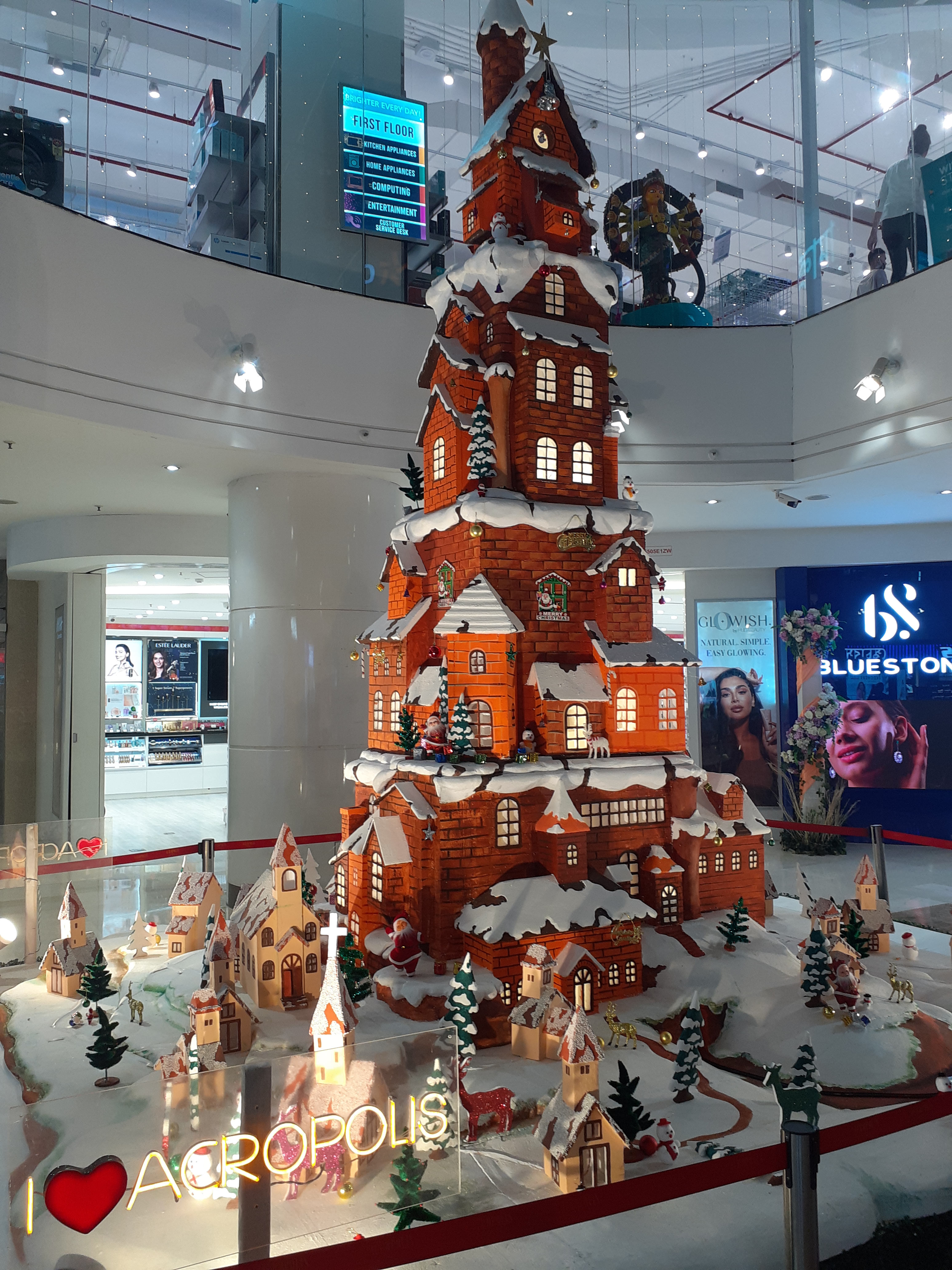 A large, intricately designed gingerbread structure resembling a tall, castle-like building covered in white icing to simulate snow.