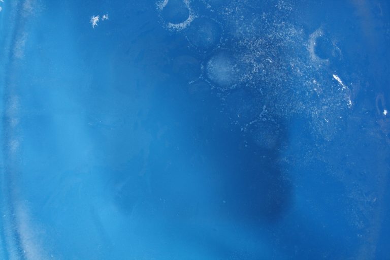 Detail of a block of frozen water in a blue container.