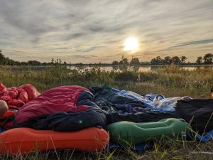 Sleeping setup in front of the sunset before a river on a bike tour.
