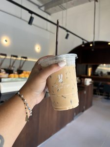A person’s hand holding up a cup of iced coffee that reads Life Begins After Coffee
