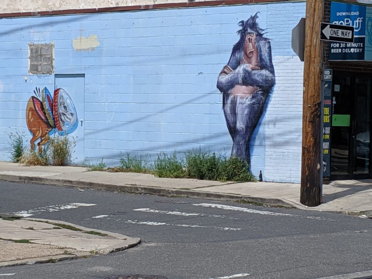 Graffiti of purple gorilla on store wall on a cracked pavement street.