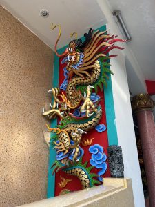 An ornate and colorful Chinese dragon statue on the wall of a building.
