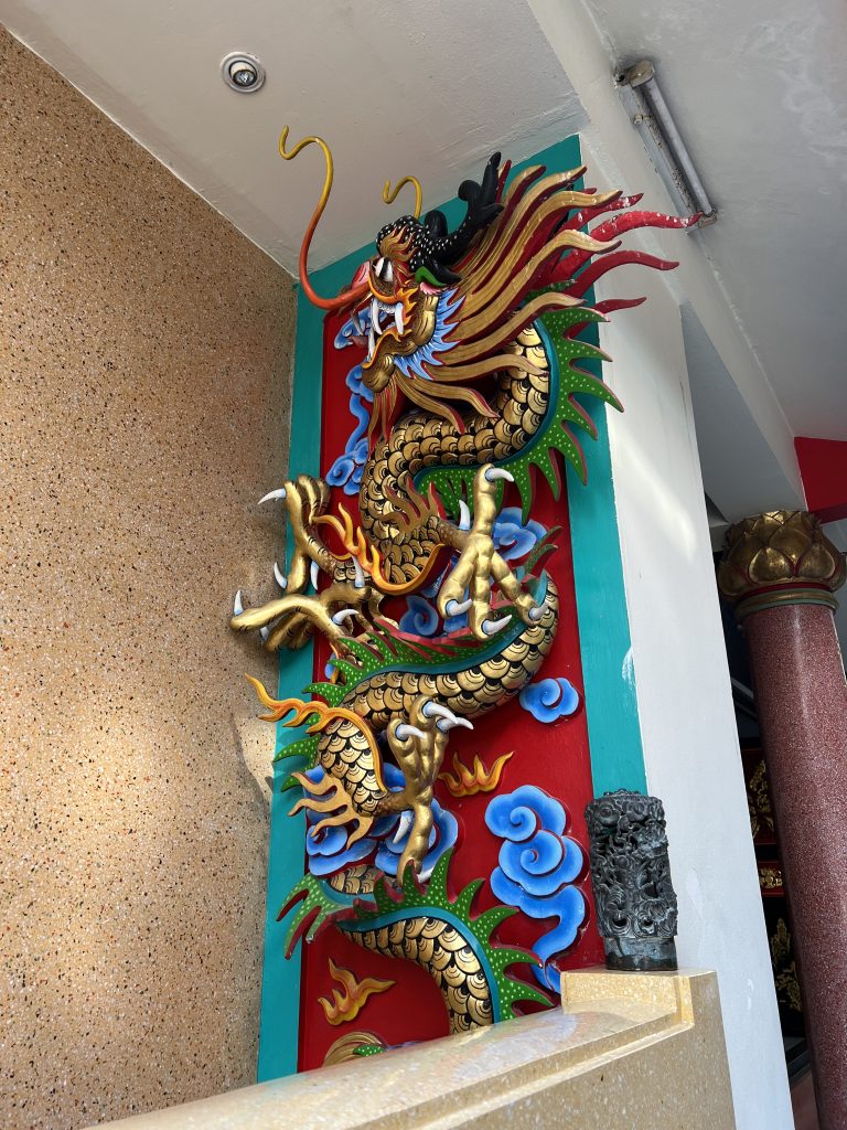 An ornate and colorful Chinese dragon statue on the wall of a building.